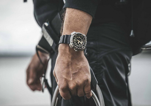 Mann mit Uhr, hält Kabel, Nahaufnahme, schwarze Kleidung, Taucheruhr