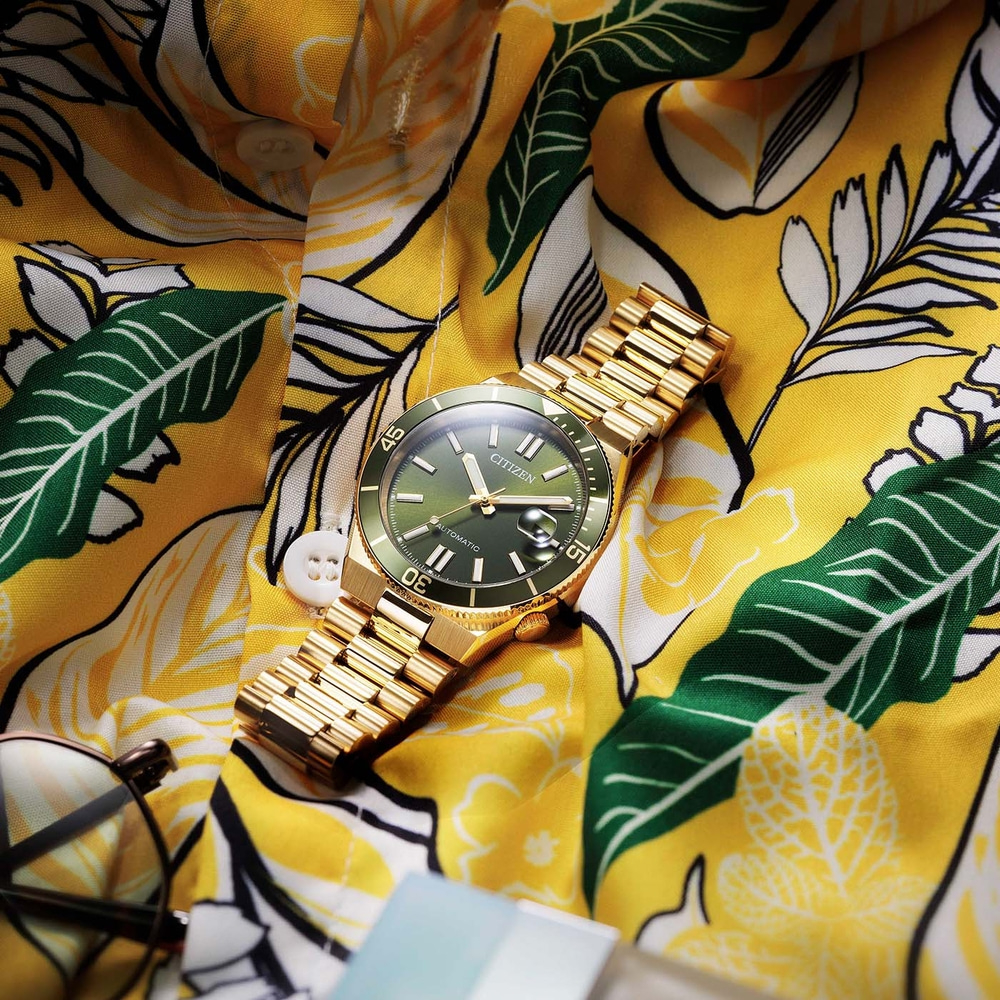 Eine goldene Citizen-Uhr auf einem gelben Blumenhemd.