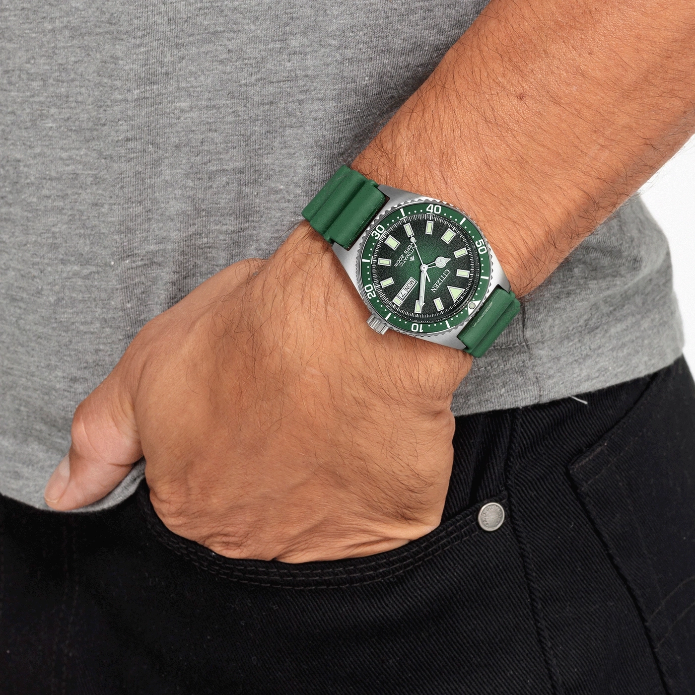Mann mit grüner Uhr und grünem Armband, Hand in der Hosentasche.