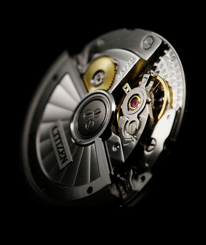 This close-up features a Citizen watch movement on a dark background, highlighting its intricate mechanical details. Polished metal components, visible golden gears, and ruby jewels showcase the precise engineering and craftsmanship.