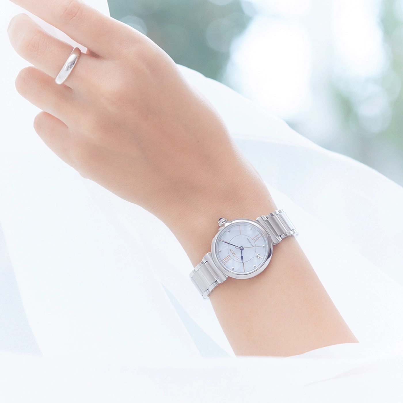 Handgelenk mit silberner Uhr und Ring, weißer Hintergrund, elegant