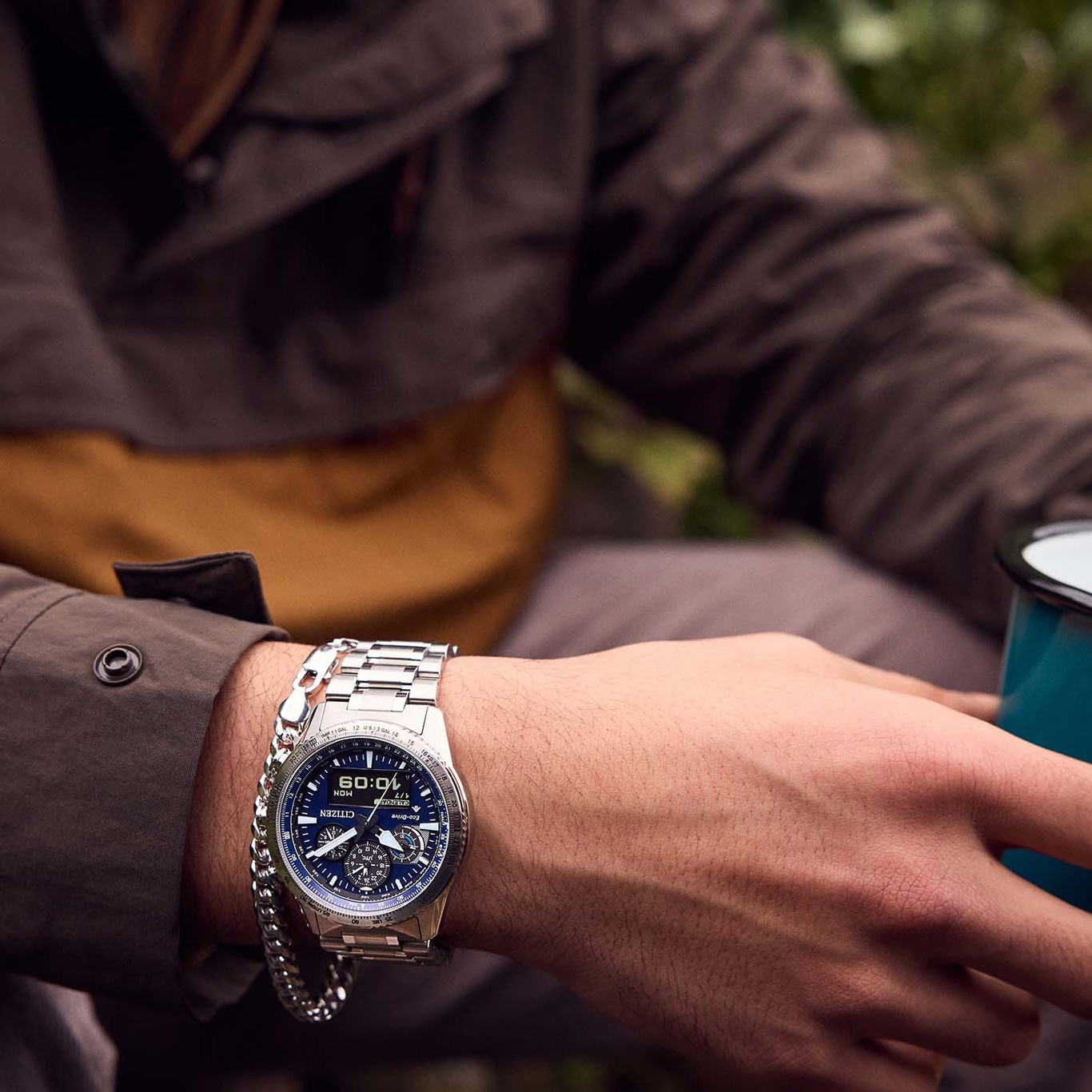 Mann mit Citizen-Uhr und Armband, hält eine Tasse in der Hand.