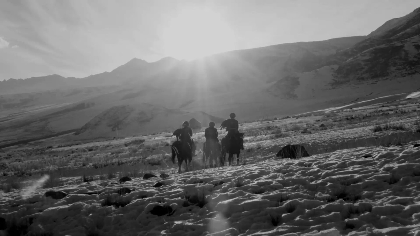 Pferde und Reiter in einer schneebedeckten Berglandschaft, Schwarzweißfotografie.