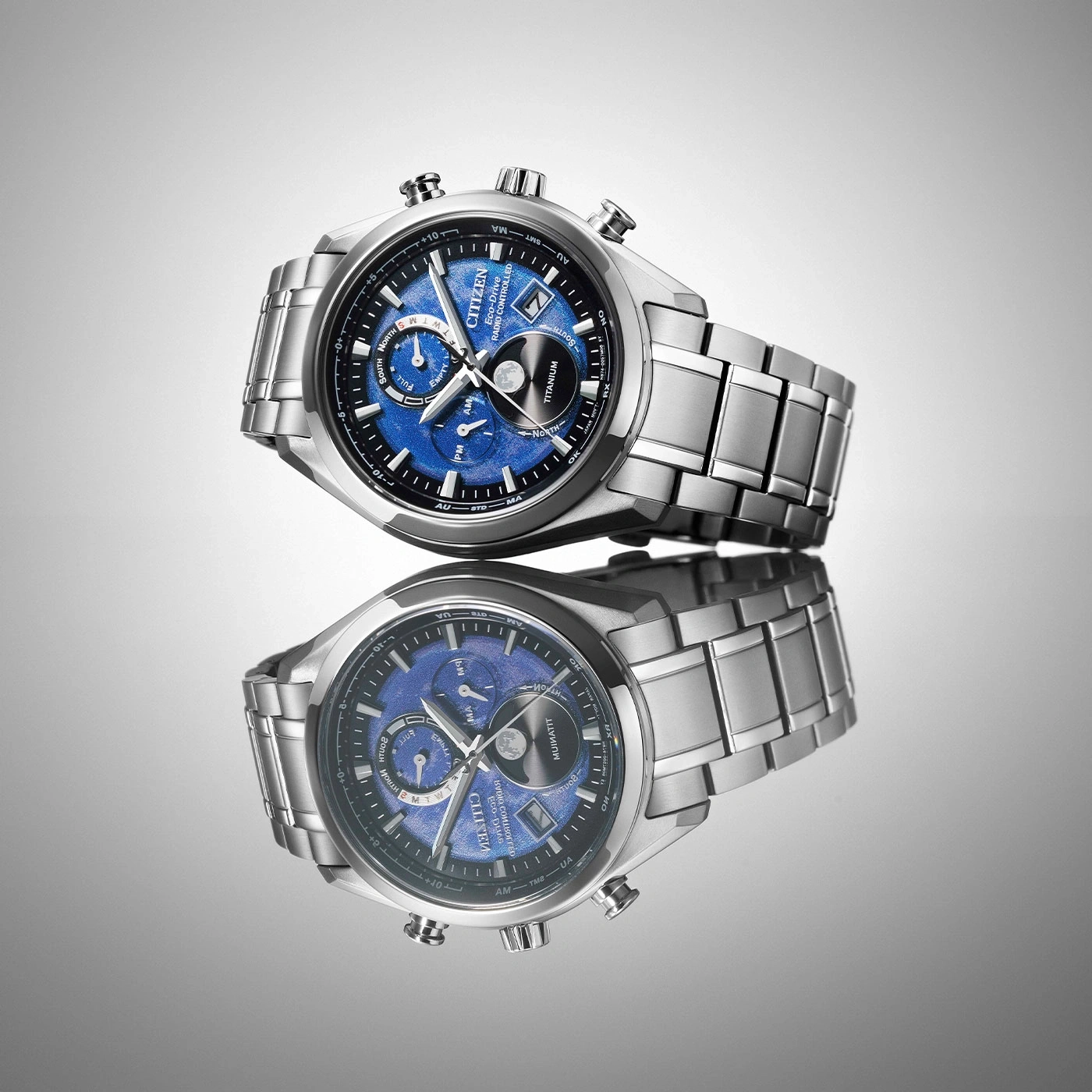 Citizen-Uhr mit blauem Zifferblatt und Titanband, reflektiert auf einer Oberfläche.