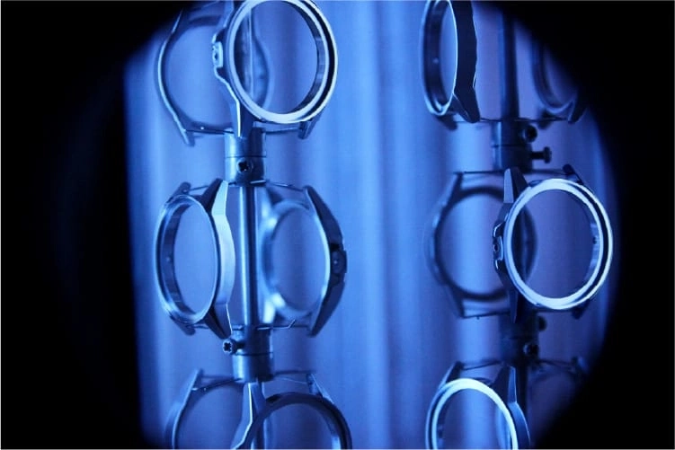 Uhrenteile auf einem Gestell, blau beleuchtet, Nahaufnahme, industrielle Szene.