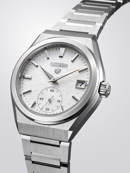 This image features a Citizen watch with a silver-toned case, textured white dial, and black strap, on a reflective surface.