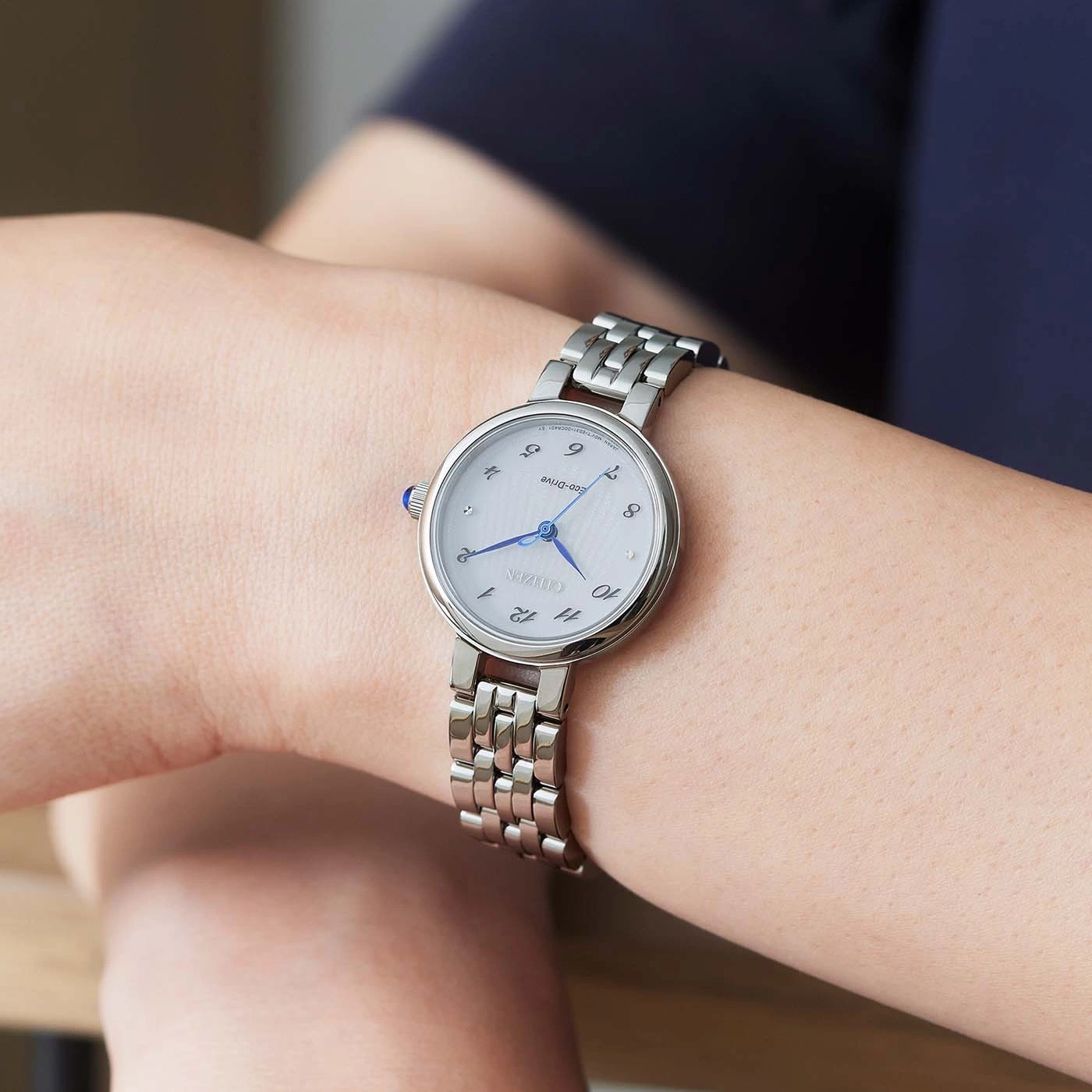 Citizen-Uhr am Handgelenk, silbernes Band, weißes Zifferblatt, blaue Zeiger, elegantes Design
