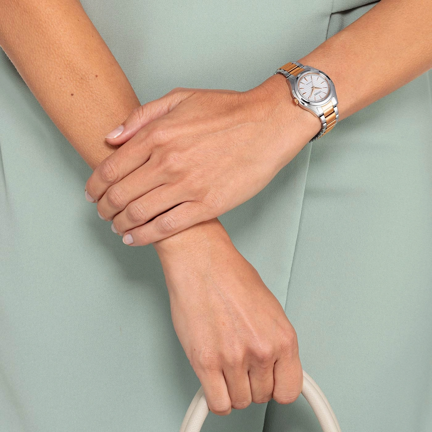 Frau mit Uhr, Handtasche, hellgrünes Kleid, Hände gekreuzt