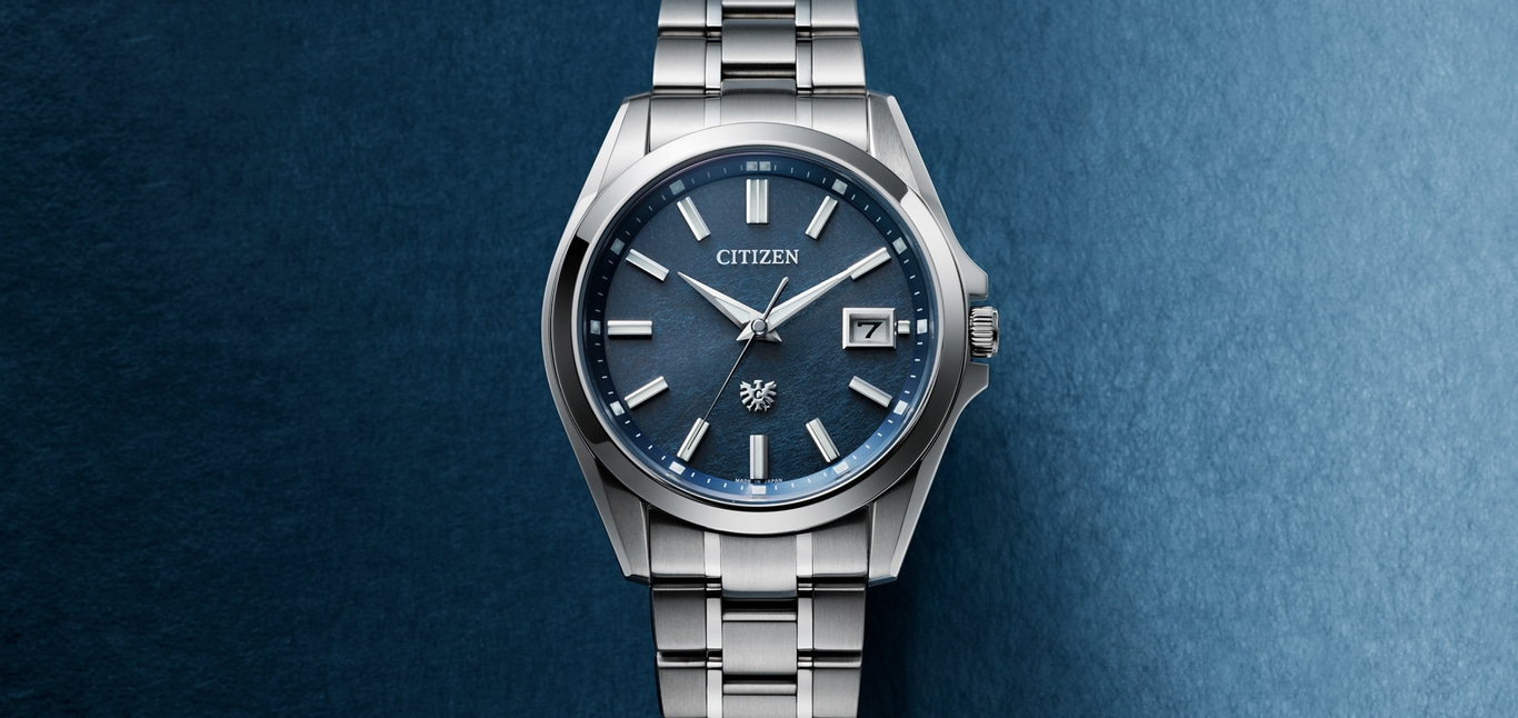 Citizen-Uhr mit blauem Zifferblatt und silbernem Armband auf blauem Hintergrund.