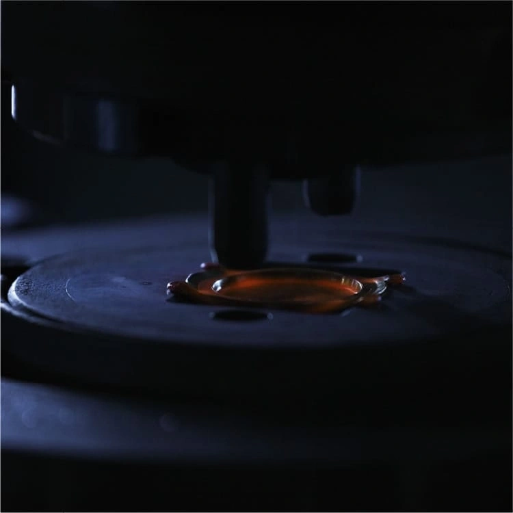 Nahaufnahme einer dunklen Maschine mit einem Tropfen oranger Flüssigkeit auf einer Platte.