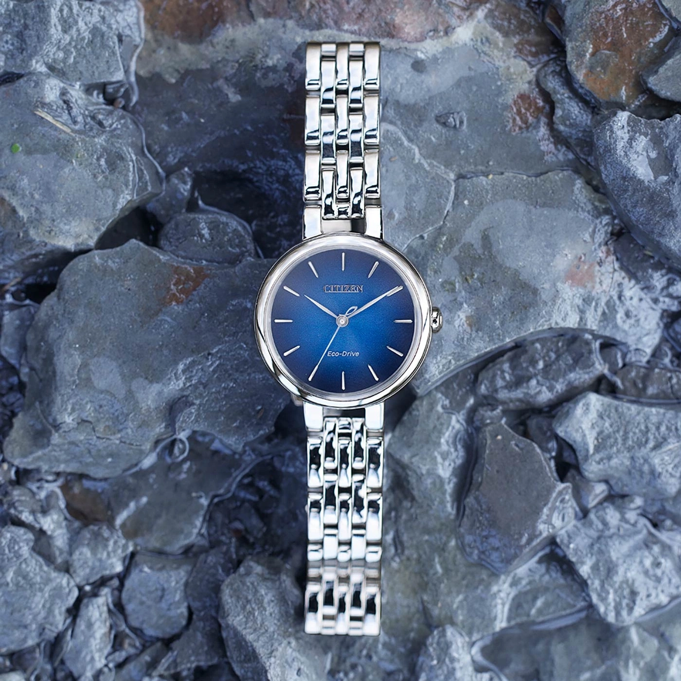 Citizen-Uhr mit blauem Zifferblatt und silbernem Armband auf felsigem Untergrund