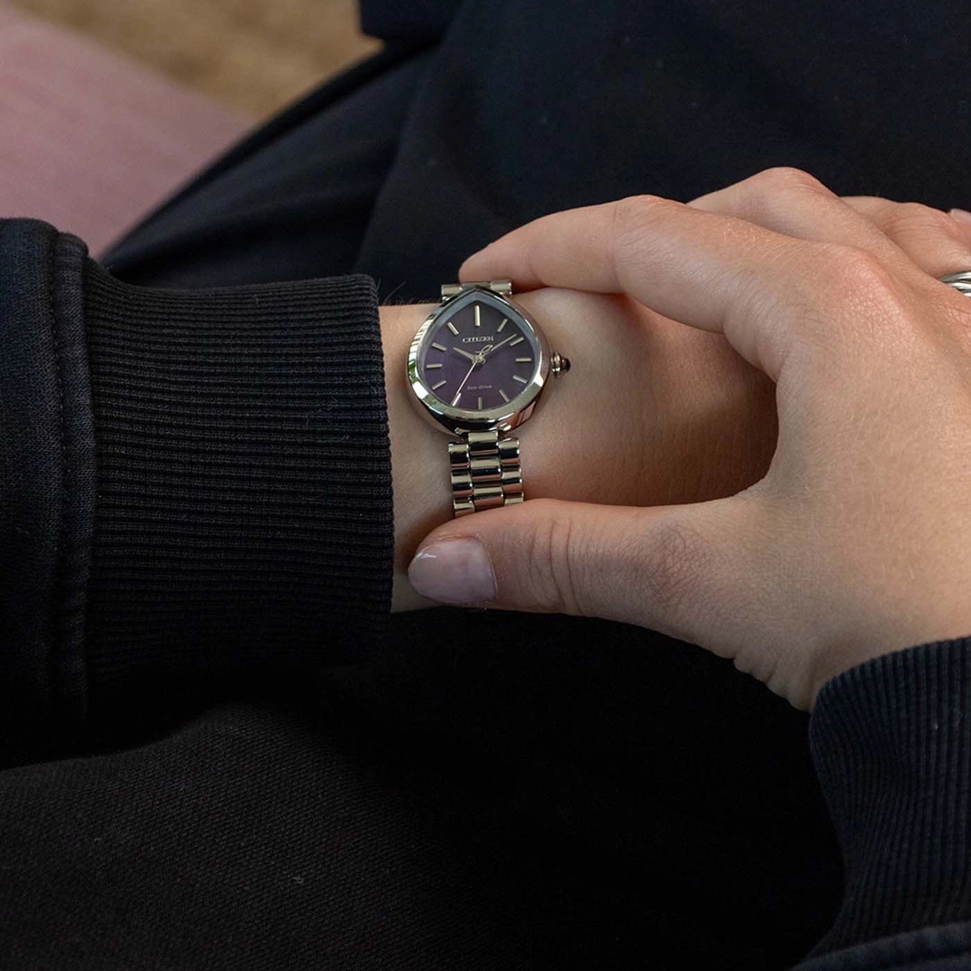Eine Frau prüft ihre Armbanduhr mit lila Zifferblatt.