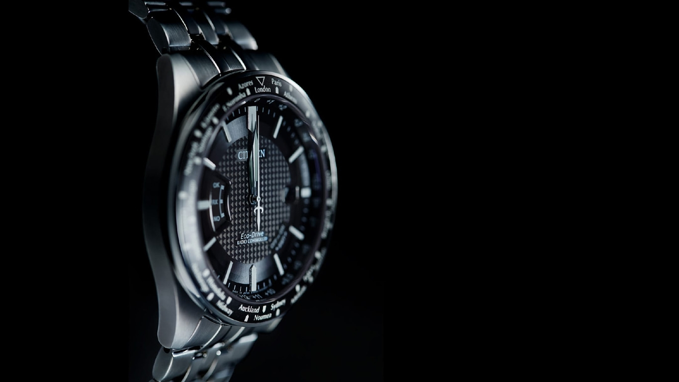 Nahaufnahme einer Citizen-Uhr mit schwarzem Zifferblatt und silbernem Armband, Zeitzonen.