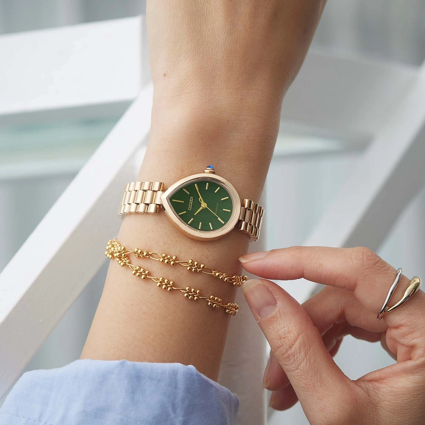 Das Handgelenk einer Frau mit einer Roségold-Uhr und einem Armband.