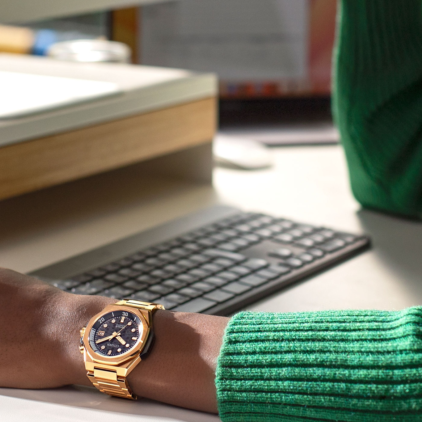 Goldene Uhr am Handgelenk, grüner Pullover, Tastatur, Schreibtisch, Büroumgebung, Citizen Uhr