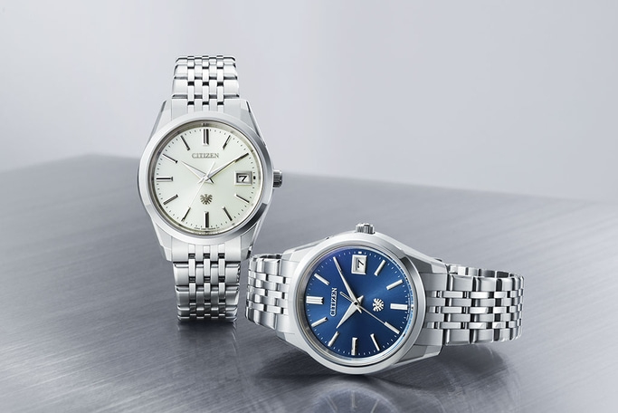 Zwei Citizen-Uhren mit silbernen Armbändern und verschiedenfarbigen Zifferblättern.