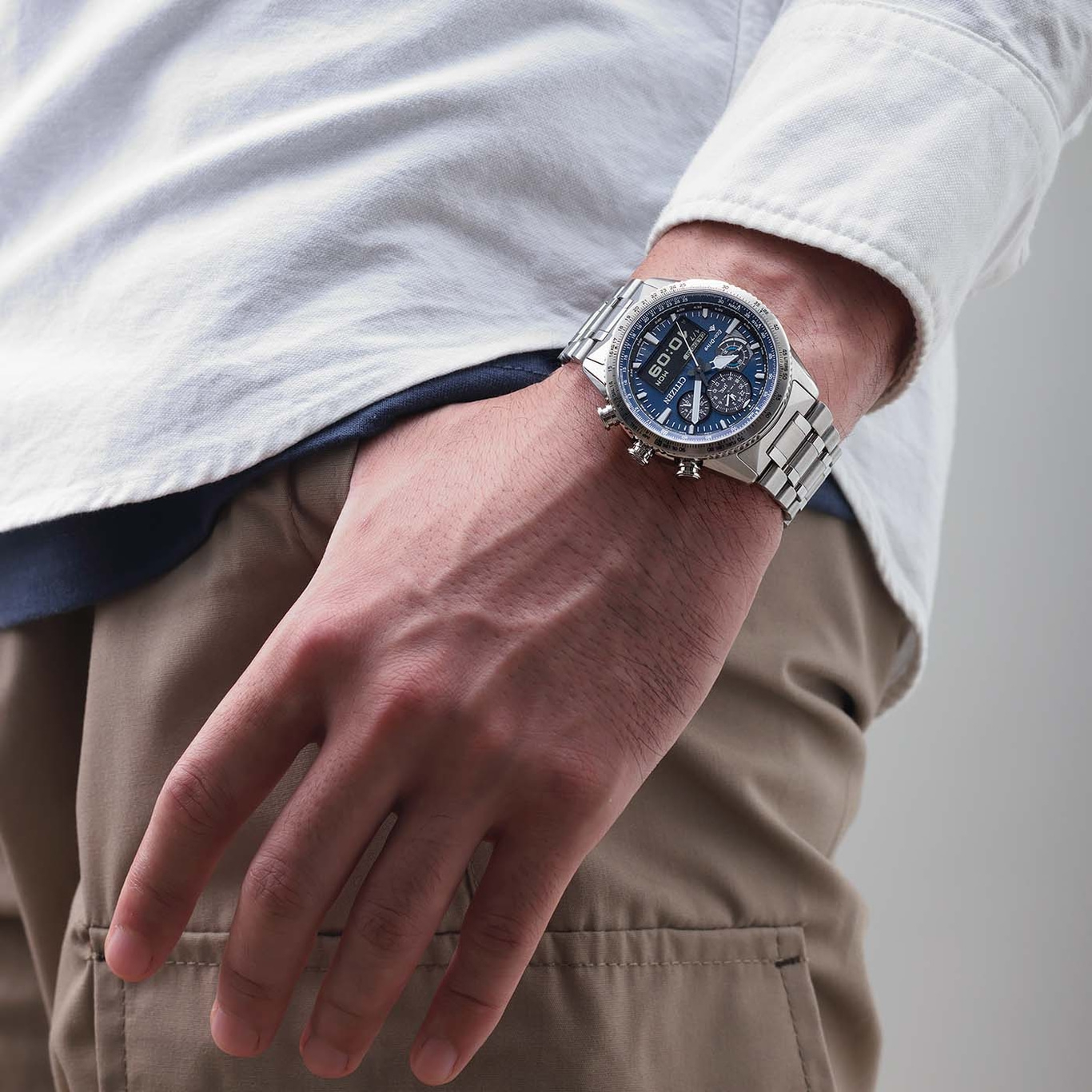 Mann trägt silberne Uhr mit blauem Zifferblatt und weißem Hemd.