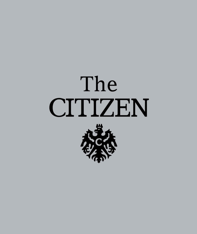 This image features 'The CITIZEN' text in black, prominently centered on a plain grey background. Below it is the brand's distinctive black eagle emblem with a 'C', signifying quality and heritage.