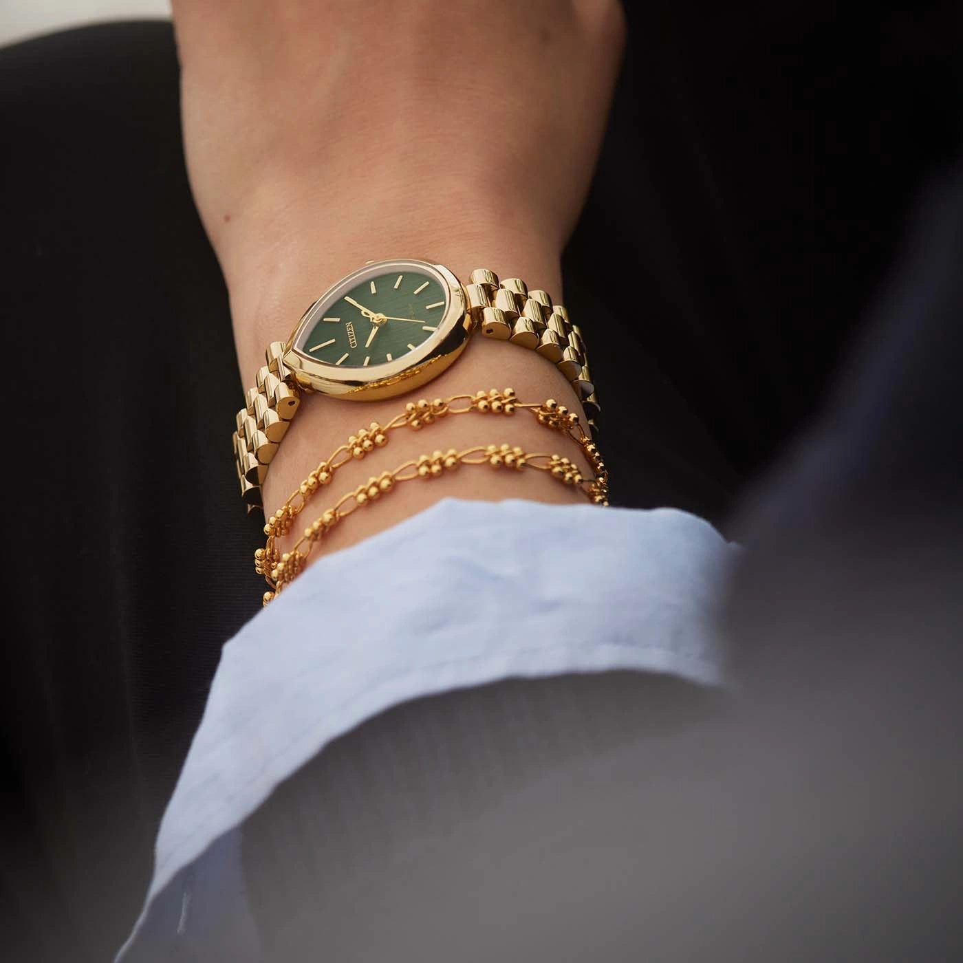Eine goldene Uhr und Armbänder am Handgelenk einer Frau