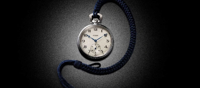 Taschenuhr mit blauen Zeigern und einer blauen Kordel auf dunklem Hintergrund.