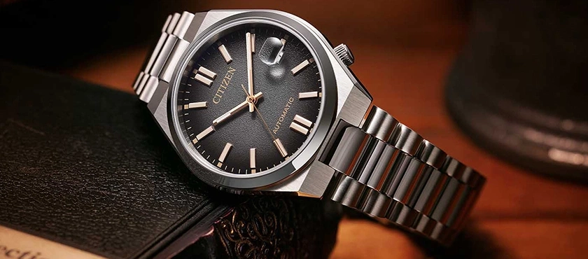 Citizen-Uhr mit schwarzem Zifferblatt und silbernem Armband auf einem Buch
