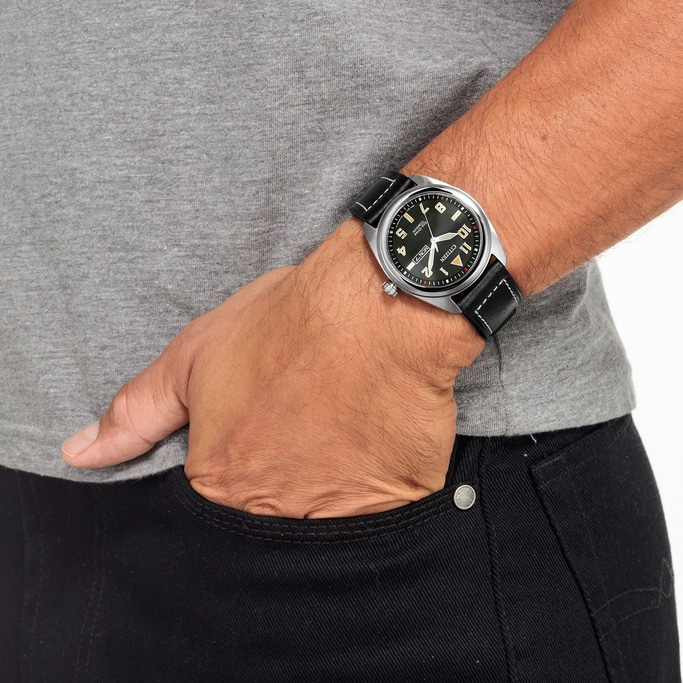 Mann mit Uhr, Hand in der Tasche, graues Hemd, schwarze Jeans, Nahaufnahme