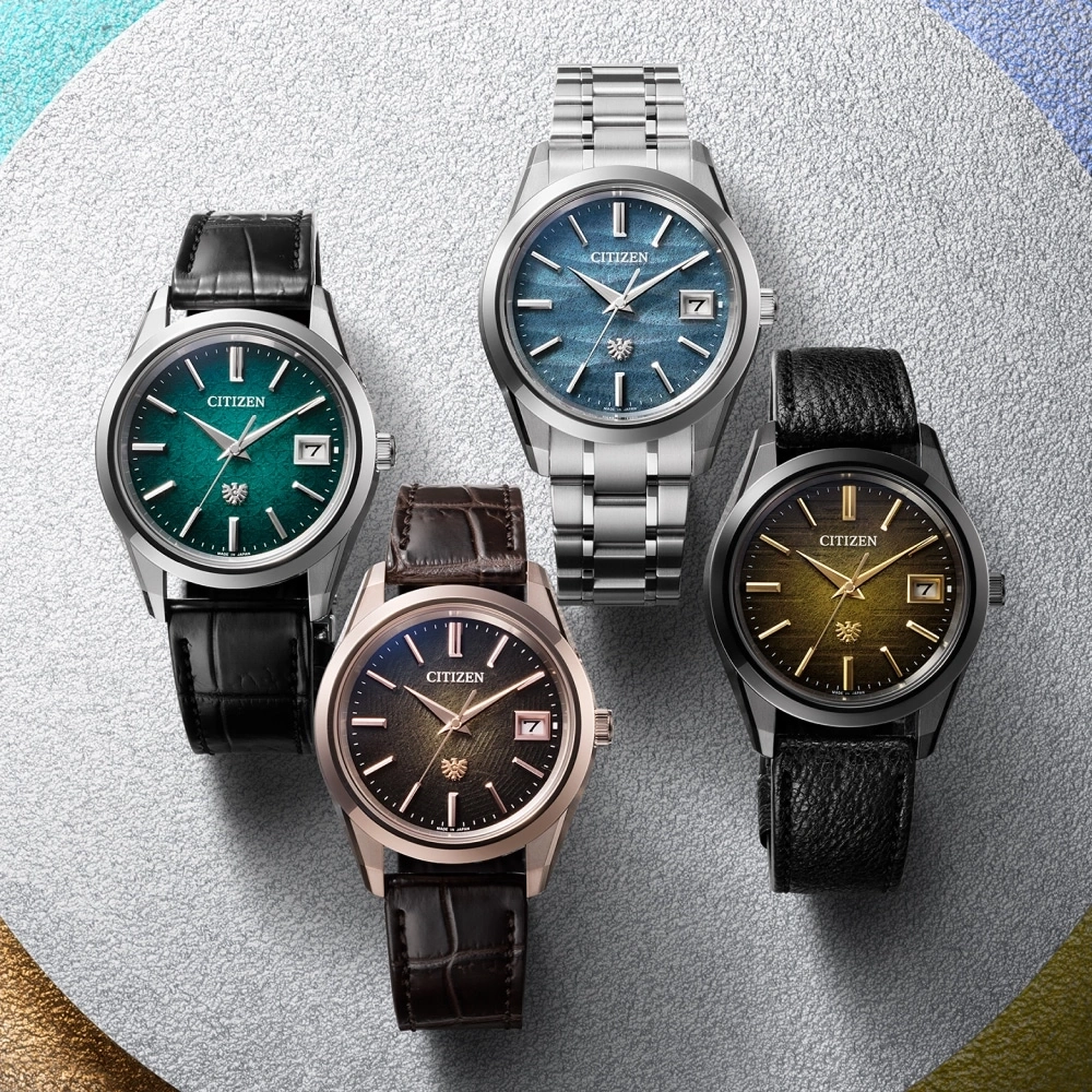 Vier Citizen-Uhren mit verschiedenen farbigen Zifferblättern und Armbändern auf silberner Oberfläche.