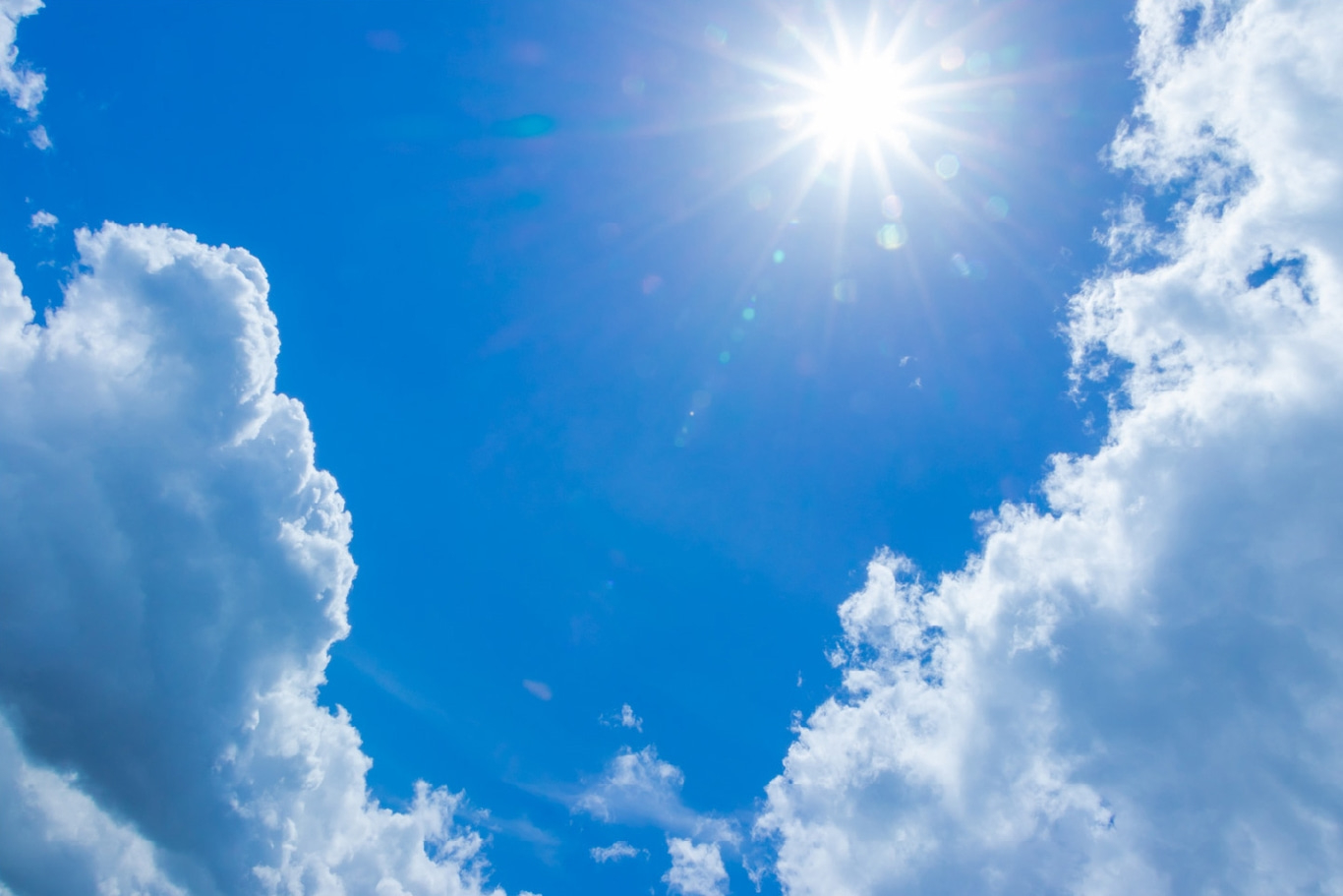 Helle Sonne scheint in einem klaren blauen Himmel mit flauschigen weißen Wolken.