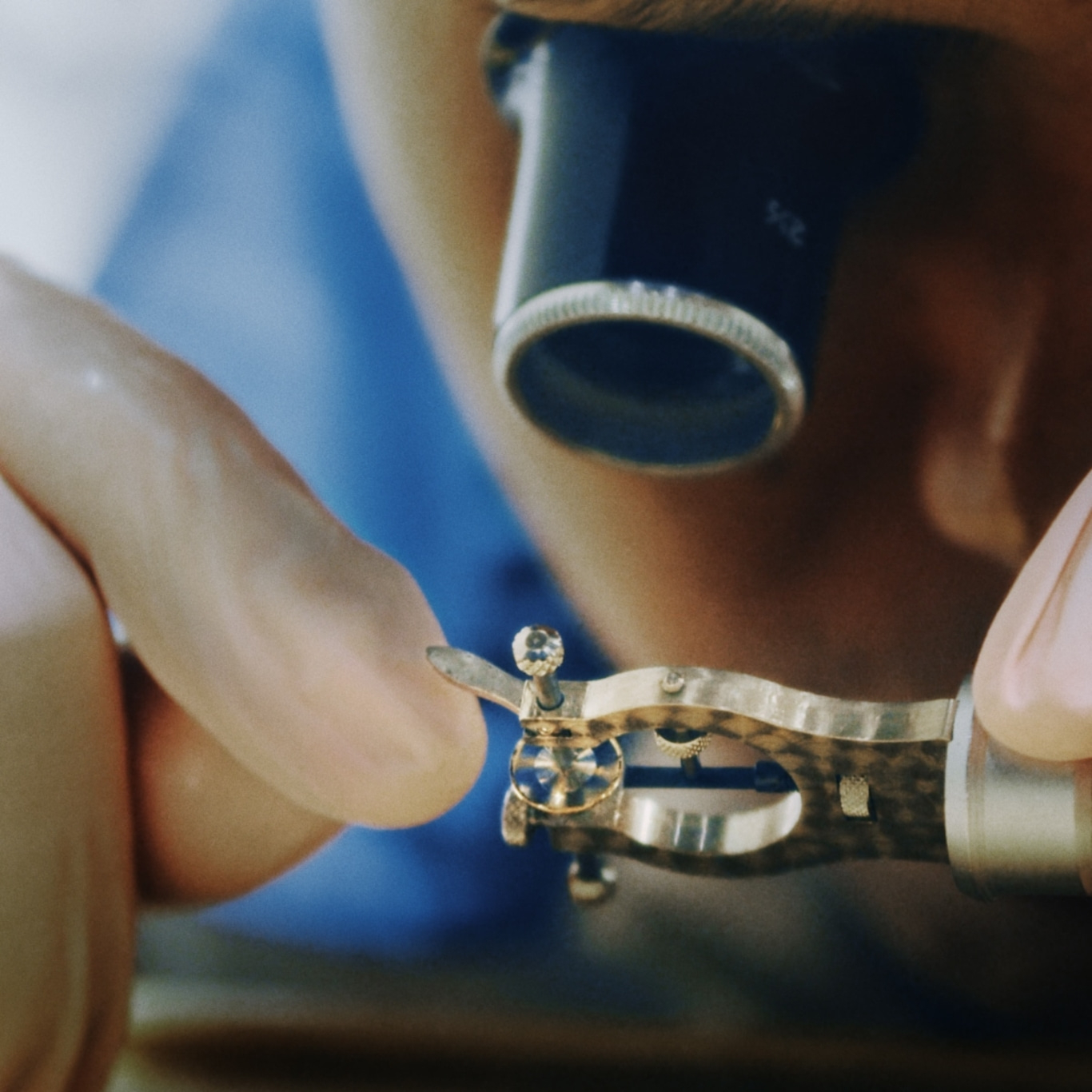 Nahaufnahme eines Uhrmachers, der mit einer Lupe an einer winzigen Uhrkomponente arbeitet.