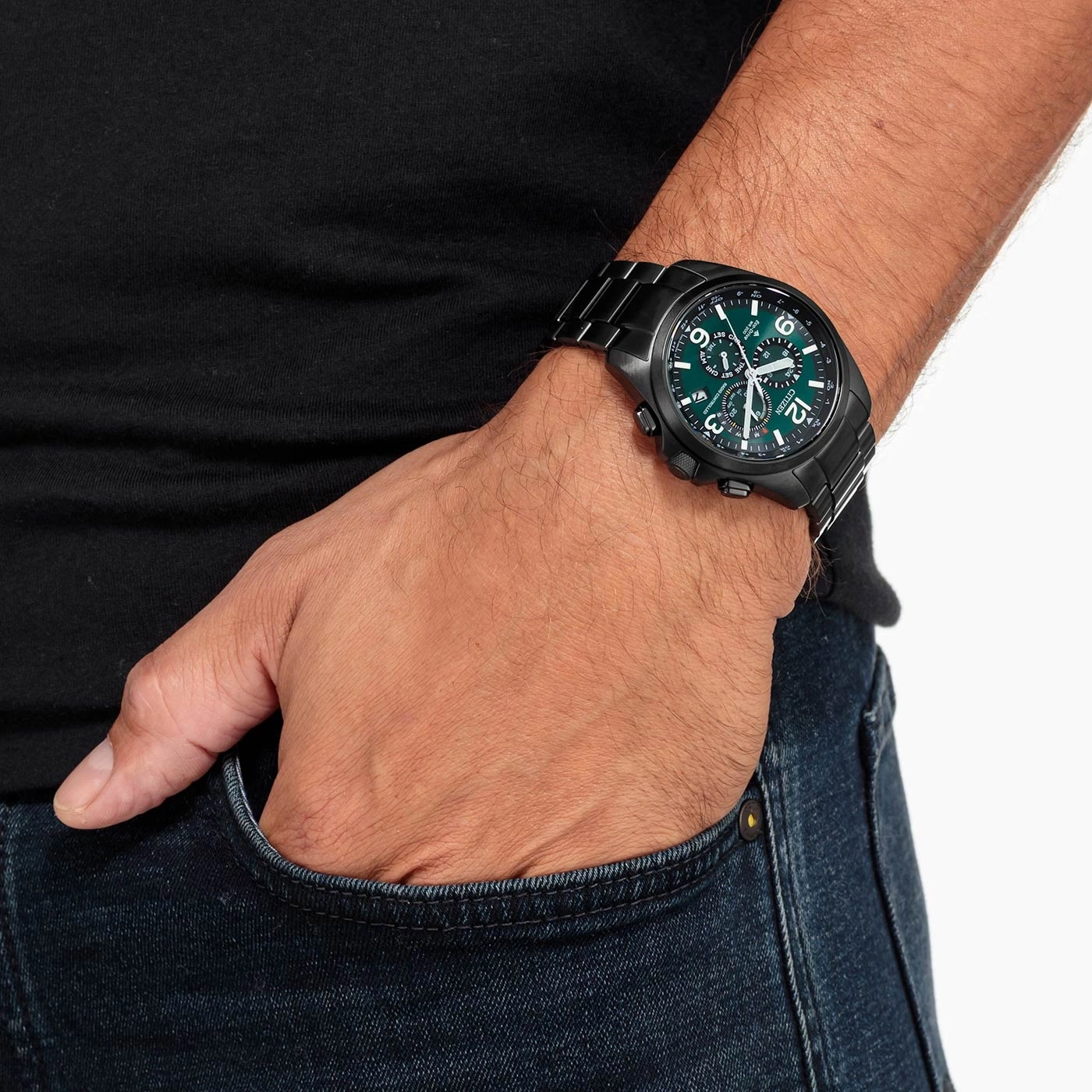 Mann mit schwarzer Uhr und grünem Zifferblatt, Hand in der Hosentasche.