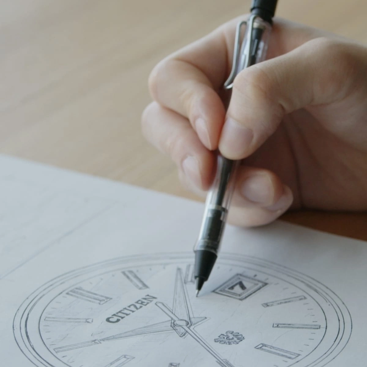 Hand zeichnet mit einem Stift ein Citizen-Uhrendesign auf Papier.