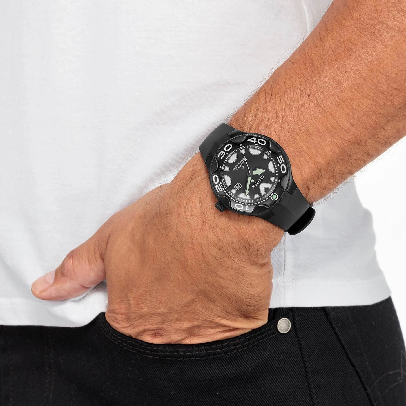Mann mit schwarzer Uhr, weißem Hemd und schwarzer Jeans, Hand in der Tasche.