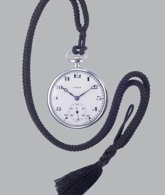 Taschenuhr mit schwarzem Kordel und Quaste, Marke Citizen, silbernes Gehäuse, weißes Zifferblatt.