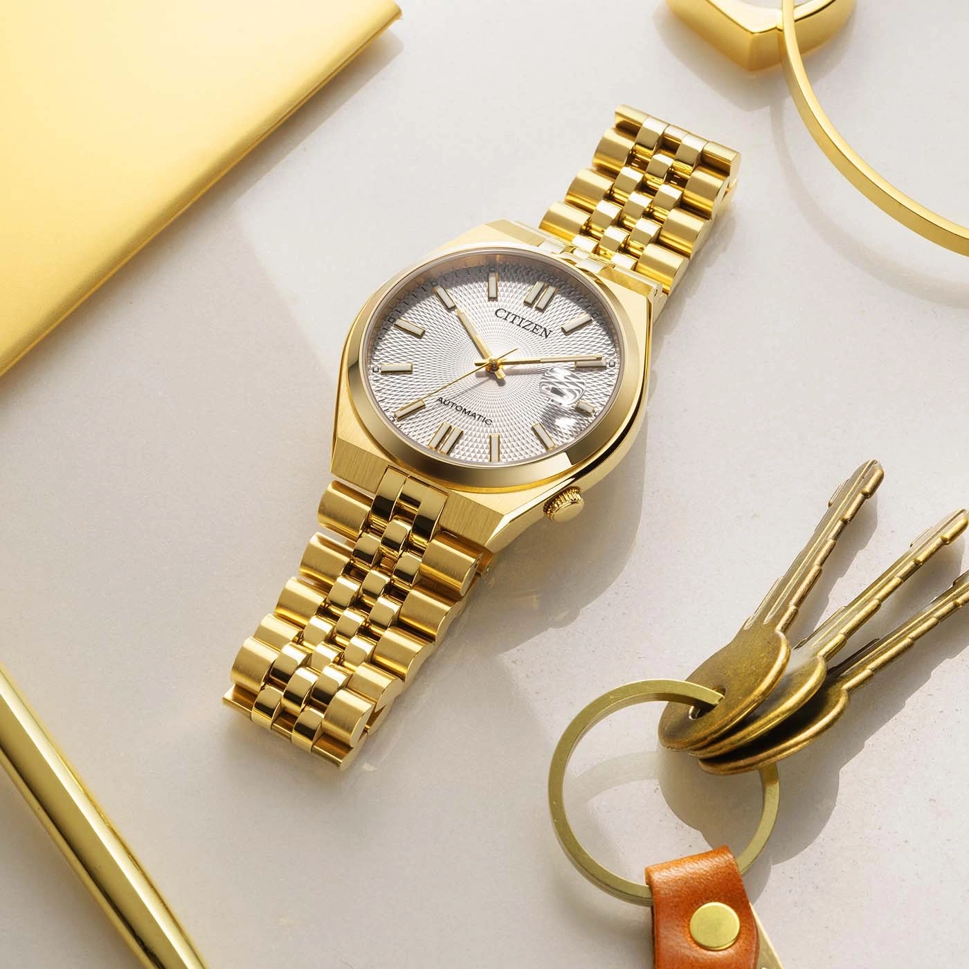 Eine goldene Citizen Automatik-Uhr mit strukturiertem Zifferblatt und Datumsanzeige.