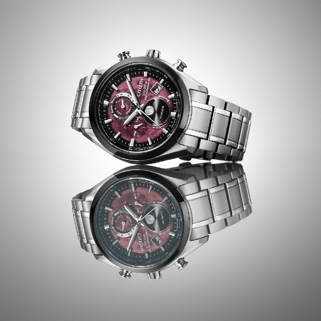 Citizen-Uhr mit rotem Zifferblatt und Titanarmband, spiegelt sich auf einer Oberfläche.