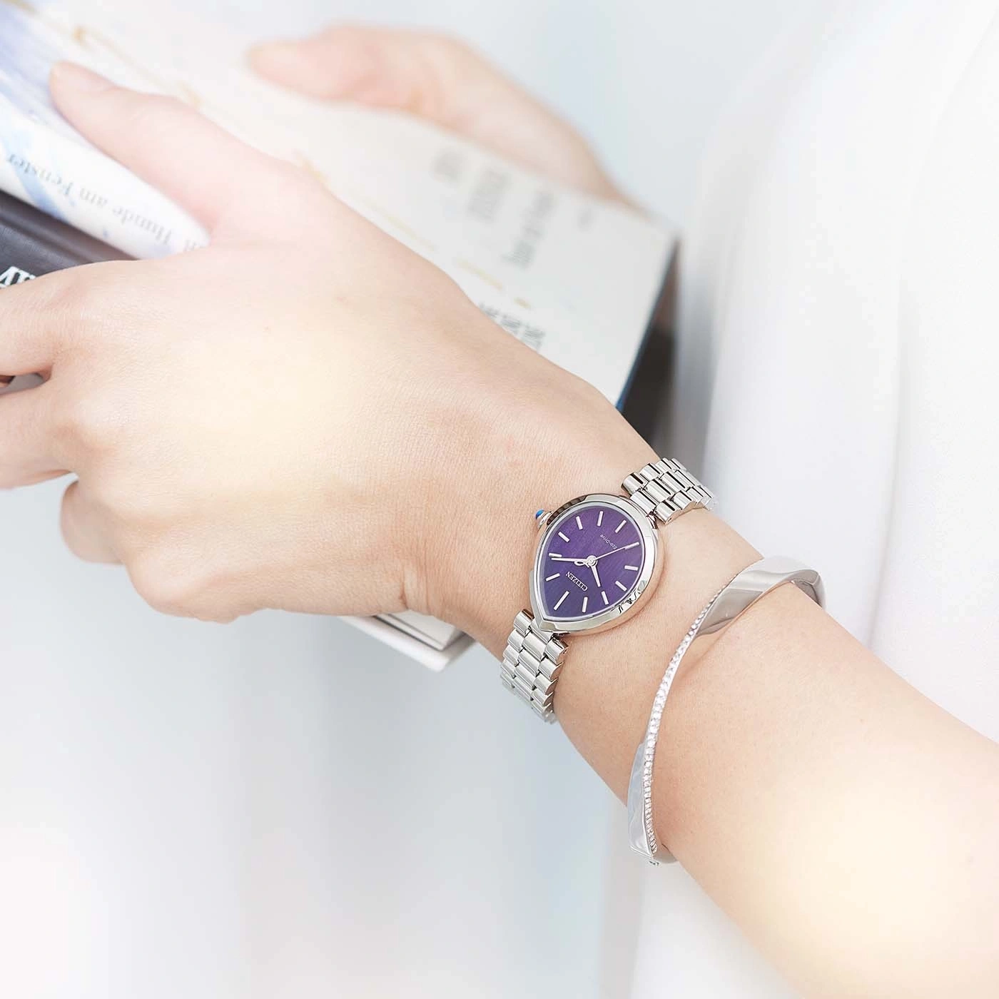 Frau trägt eine lila Uhr und ein Silberarmband, liest.