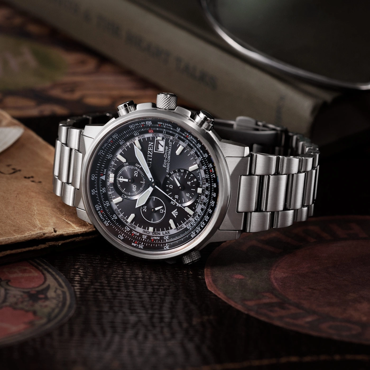 Citizen-Uhr mit schwarzem Zifferblatt und silbernem Armband auf Holzoberfläche.