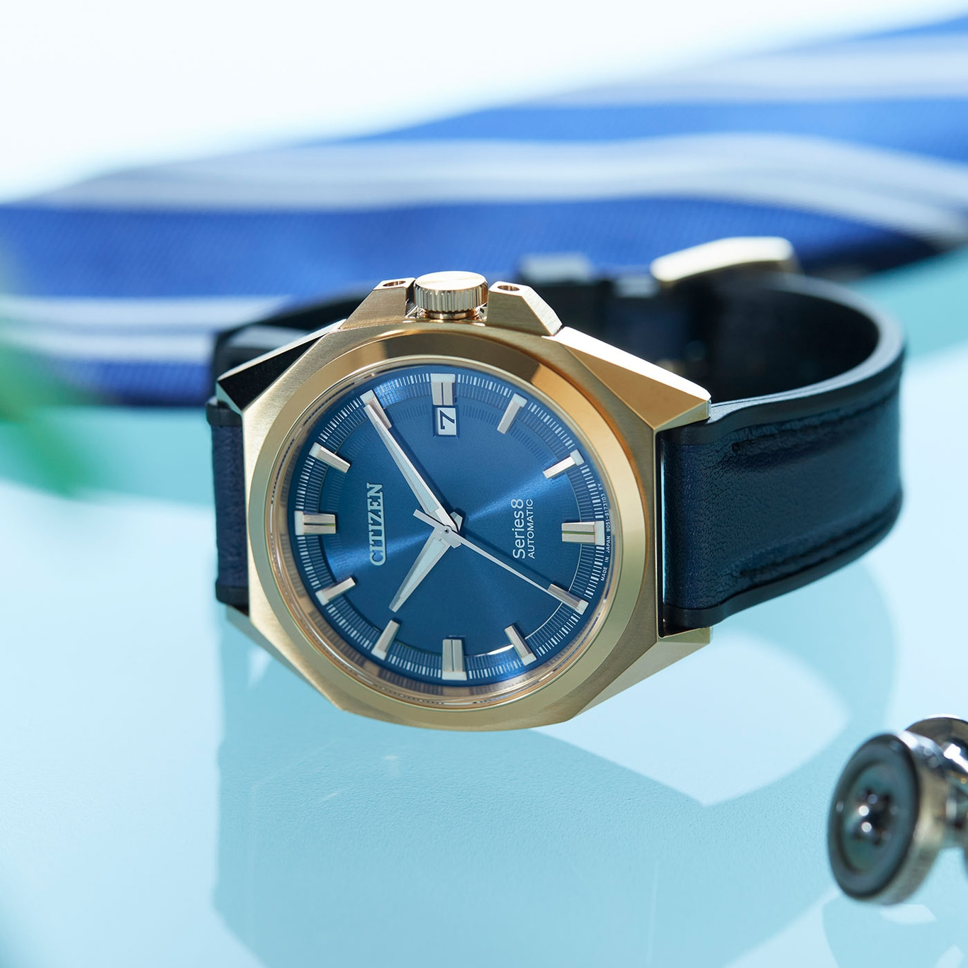 Nahaufnahme einer goldenen Uhr mit blauem Zifferblatt und schwarzem Armband.