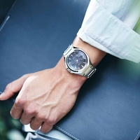 Mann mit silberner Uhr, hält eine dunkelblaue Mappe in der Hand.