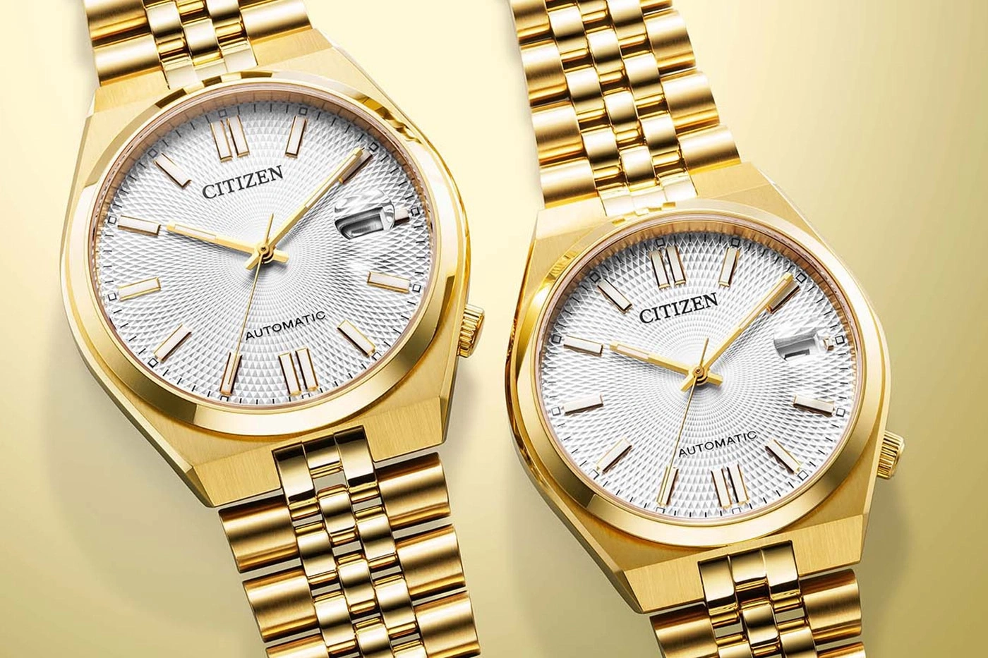 Zwei goldene Citizen Automatikuhren mit weißen, strukturierten Zifferblättern.