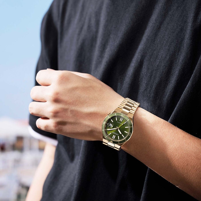Mann trägt eine goldene Citizen-Uhr mit grünem Zifferblatt.