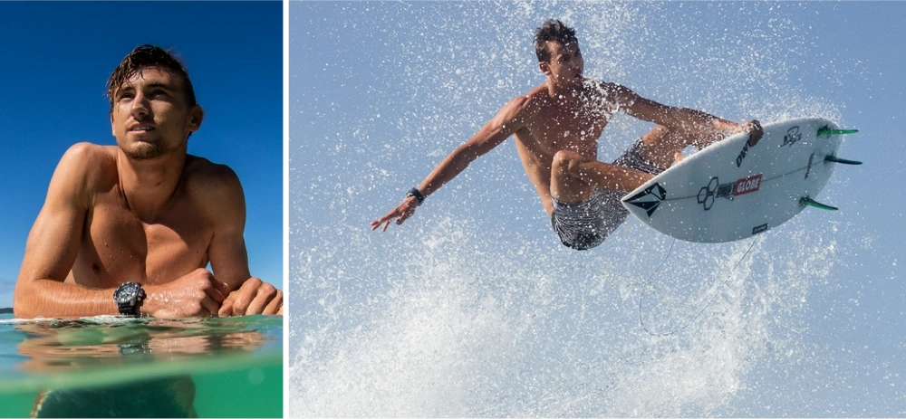 Surfer in Aktion, in der Luft, mit Surfbrett und Wasserspritzern vor blauem Himmel.