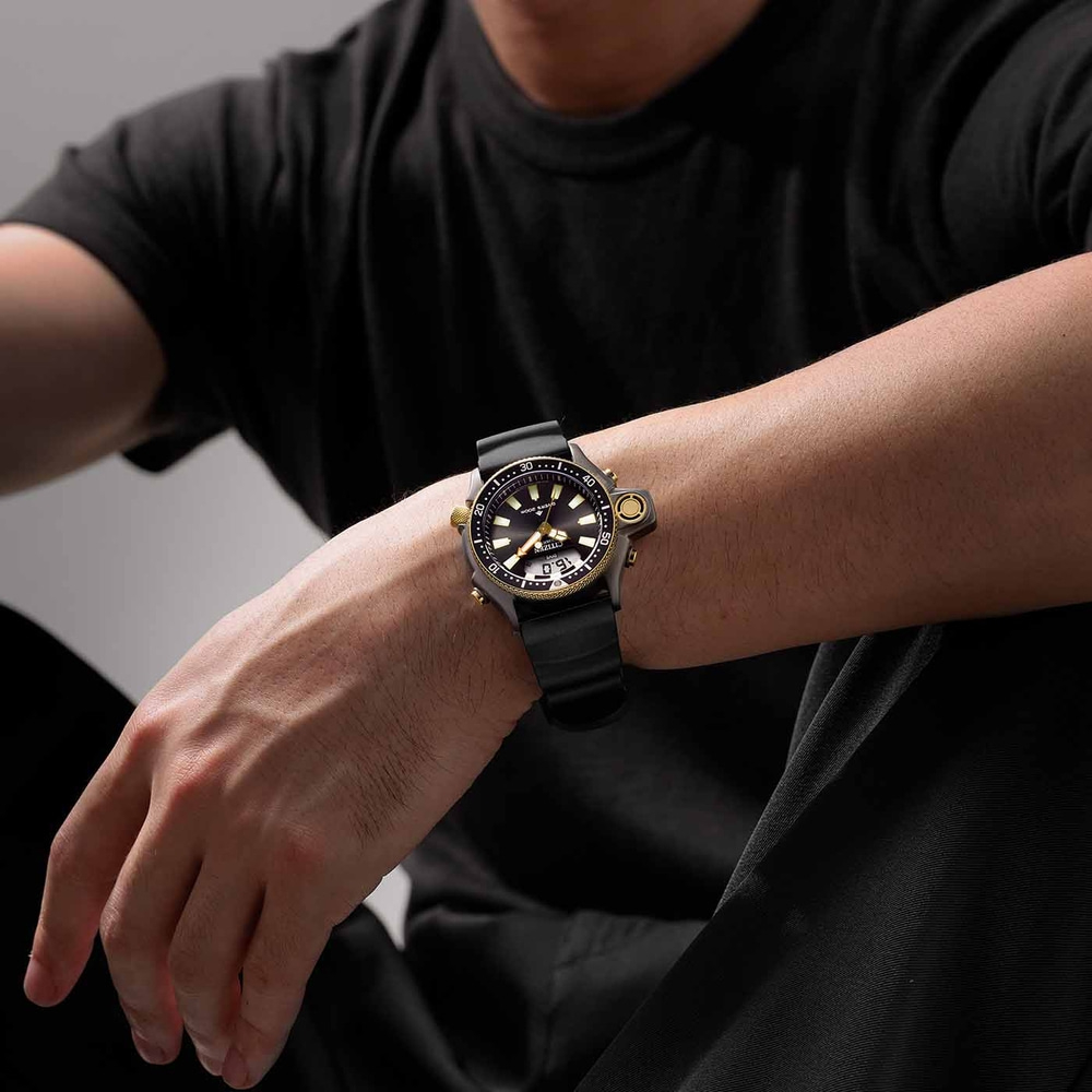 Mann trägt eine schwarze Uhr mit schwarzem Armband und goldenen Akzenten.