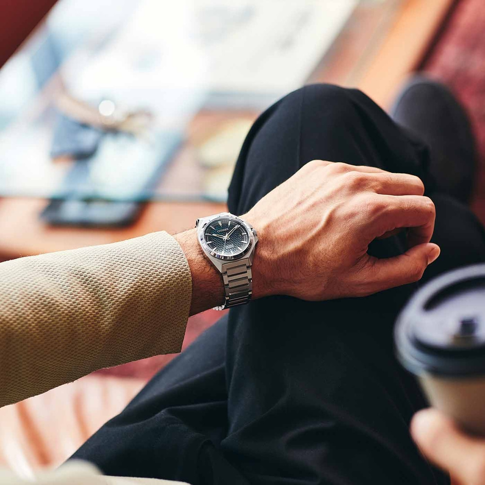 Mann mit Citizen-Uhr, sitzt mit Kaffee, Nahaufnahme. Stilvolles Accessoire.