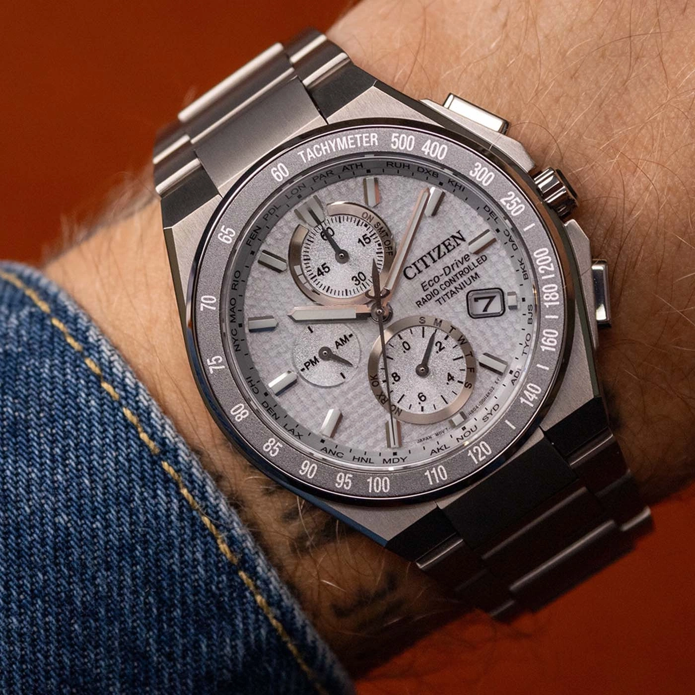 Nahaufnahme einer Citizen Eco-Drive Titan-Uhr am Handgelenk mit Tachymeter und Weltstädten.