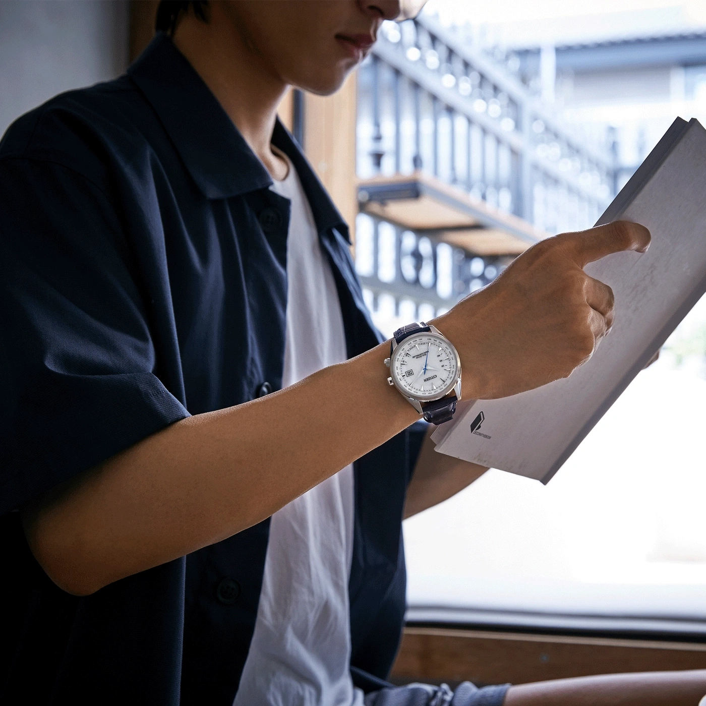 Mann mit Uhr, liest Papier, mit blauer Jacke und weißem Hemd.