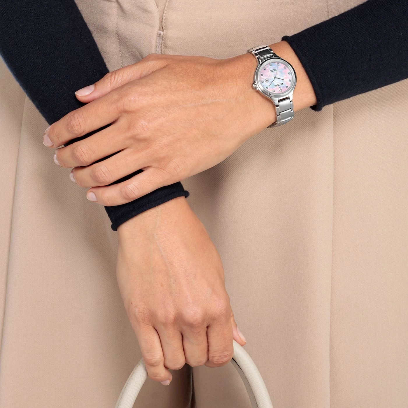 Frau mit Uhr, Handtasche, schwarzem Ärmel und beiger Hose. Nahaufnahme.