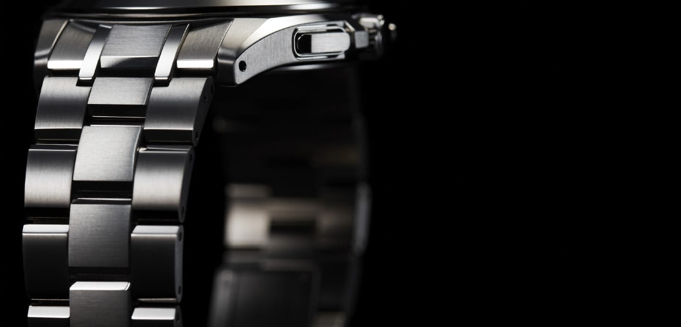 Nahaufnahme einer silbernen Uhr mit schwarzem Hintergrund, die das Armband der Uhr zeigt.