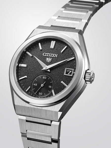 This image features a Citizen watch with a silver-toned case, textured white dial, and black strap, on a reflective surface.