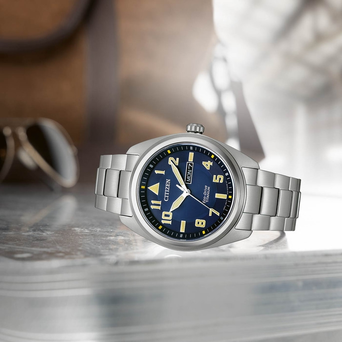 Citizen-Uhr mit blauem Zifferblatt und silbernem Armband auf reflektierender Oberfläche